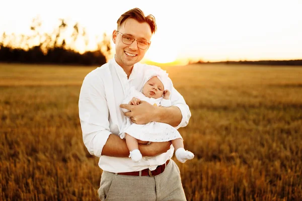 Портрет красивого отца с очаровательной маленькой дочерью на поле, заботливый папа держать милый новорожденный девочка в руках, нежные семейные моменты, воспитания и отцовства концепции — стоковое фото