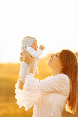 Tarlada yeni doğmuş güzel bir bebeği olan sevimli bir kadın, şefkatli bir anne, tatlı bir kız çocuğu, mutlu aile anları, ebeveynlik ve annelik kavramı.  