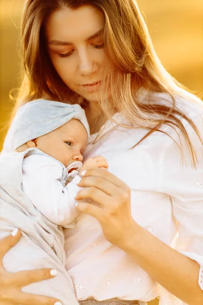 Мама с милой маленькой дочкой в поле, симпатичная женщина держит на руках симпатичную новорожденную девочку, заботливая мама наслаждается каждым моментом прощания, материнства — стоковое фото