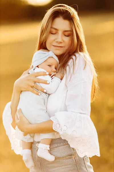 Gyönyörű anya szép kislánya a területen, csinos nő tartsa aranyos újszülött kislány karját, gondoskodó anya élvezni minden pillanatát szülői, anyaság koncepció — Stock Fotó