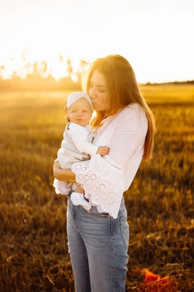Очаровательная мать с красивой маленькой дочерью на поле, красивая женщина держать милый новорожденный ребенок в руках, заботливая мама нежно поцеловать крошечную девочку, концепция материнства — стоковое фото