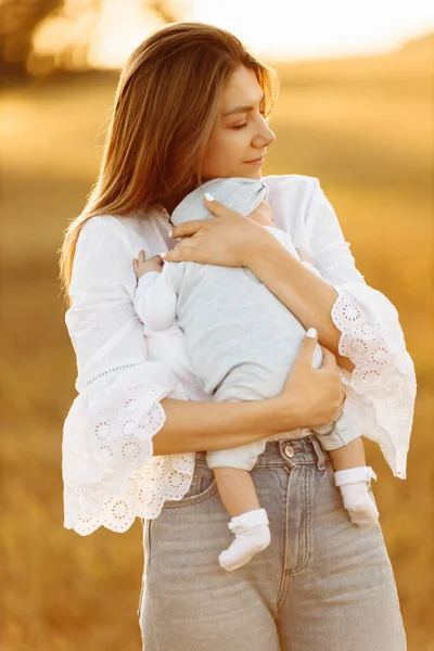 Gyönyörű anya szép kislánya a területen, csinos nő tartsa aranyos újszülött kislány karját, gondoskodó anya élvezni minden pillanatát szülői, anyaság koncepció — Stock Fotó