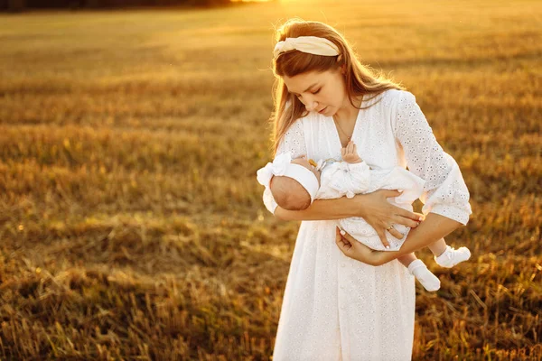 Liebevolle Mutter mit schöner kleiner Tochter, die auf dem Feld spaziert, fürsorgliche Mutter hält niedliches neugeborenes Mädchen im Arm, zarte Mutterschaftsmomente, Kindheits- und Mutterschaftskonzept — Stockfoto