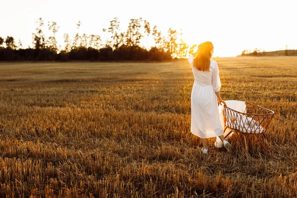 Härlig kvinna nära liten säng med nyfödd flicka på fältet, lycklig mamma tillbringa tid med liten dotter, lycklig familj stunder, föräldraskap och moderskap koncept — Stockfoto