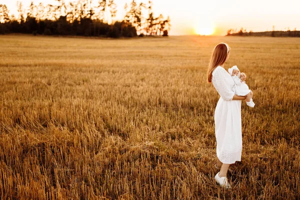 Mãe maravilhosa com linda filhinha andando no campo, mãe elegante segurar bonito bebê recém-nascido menina nos braços, momentos familiares felizes, parentalidade e conceito de maternidade — Fotografia de Stock