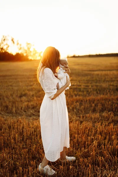 Loving mother with beautiful little daughter walking at the field, caring mom hold cute newborn baby girl in arms, tender maternity moments, childhood and motherhood concept — Stock Photo, Image