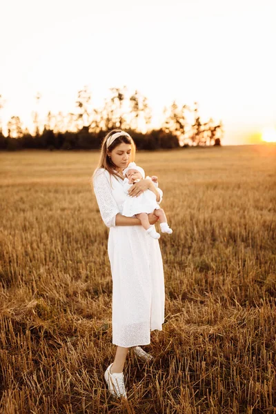 Mãe maravilhosa com linda filhinha andando no campo, mãe elegante segurar bonito bebê recém-nascido menina nos braços, momentos familiares felizes, parentalidade e conceito de maternidade — Fotografia de Stock
