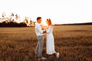 Mutlu bir aile tarlada yürüyor, şefkatli bir baba kucağında tatlı bir bebek kız çocuğu, muhteşem bir anne kucağında küçük bir kızın küçük ellerini tutuyor, ebeveynlik kavramı.