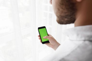 Yakışıklı delikanlı Smartphoneisolated beyaz kullanır. 