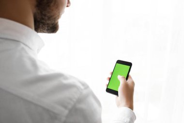 Yakışıklı delikanlı Smartphoneisolated beyaz kullanır. 