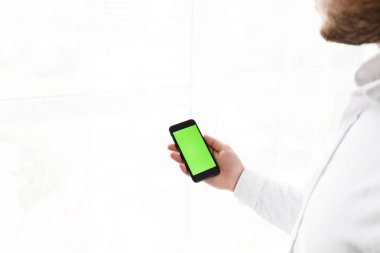 Yakışıklı delikanlı Smartphoneisolated beyaz kullanır. 