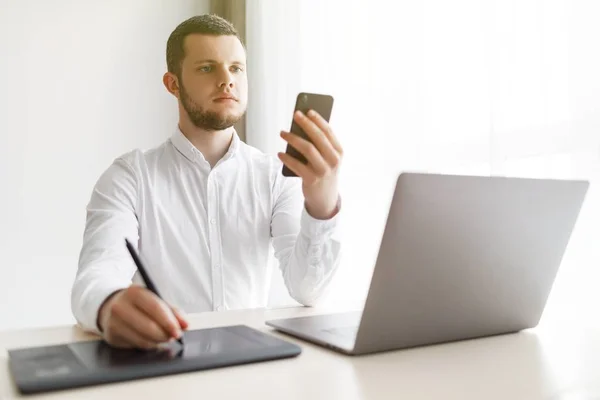 Genç adam grafik tablet ve smartphone evde kullanma 