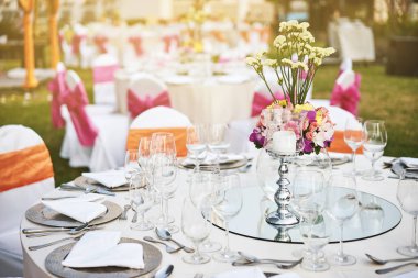 Resepsiyon akşam yemeği sofra ile boş bardak su, şarap ve çiçek dekorasyonu ile dinnerwear ve beyaz kumaş kapak sandalye pembe kanat ile düğün