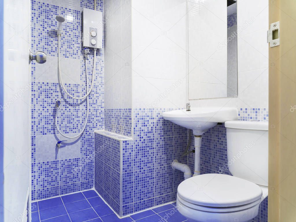 Clean restroom with white toilet, washbasin and mirror decoration with small blue ceramic color, Old style washroom.