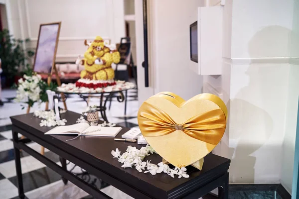 Golden box heart shape for drop the wedding envelopes at front reception with sign book on the table