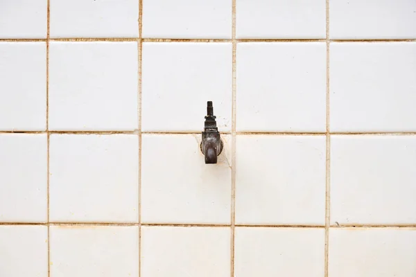 Front view of white ceramic wall with stained and broken faucet water tap for drinking water in rural school