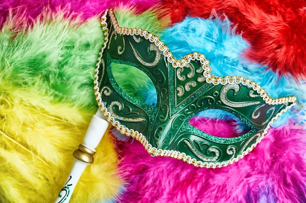 Yakın çekim yeşil karnaval maskesi, Venedik Maske (Opera maskesi) Beyaz ahşap sap üzerinde renkli yumuşak tüylü tüyler sarı, pembe, mavi, kırmızı ve yeşil, fantezi kavramı, Photo booth'den aksesuarlar