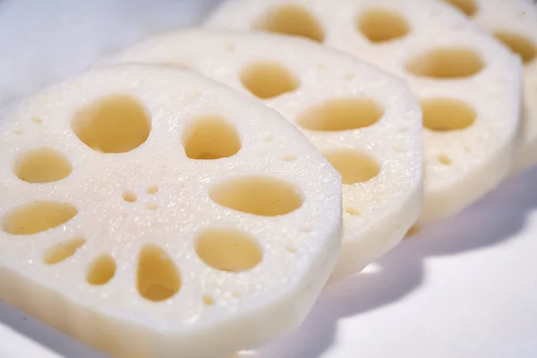 A white plate of lotus roots chopped sliced with selective focus close-up the holes inside the roots with shallow depth of field