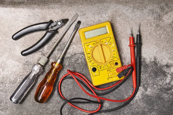 DIY home electricity working tools concepts, Old screwdrivers, pliers and electricity voltage multimeter on dusty cement background
