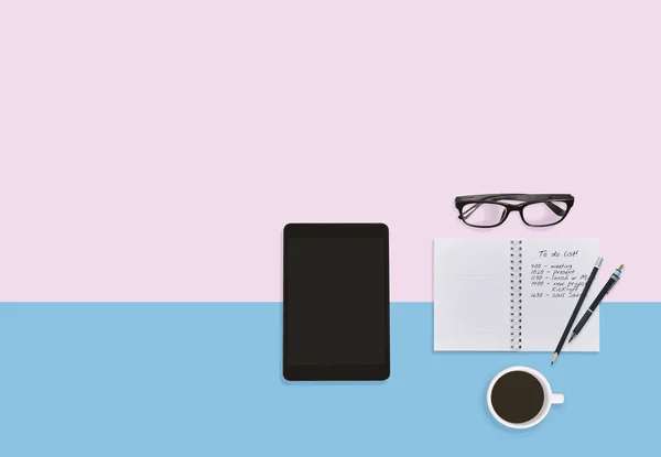 Personal business man working space desktop in pastel color background with notes in notebook, eyeglasses, tablet, pen, pencils and coffee cup with copy space. Business plan working space concept.