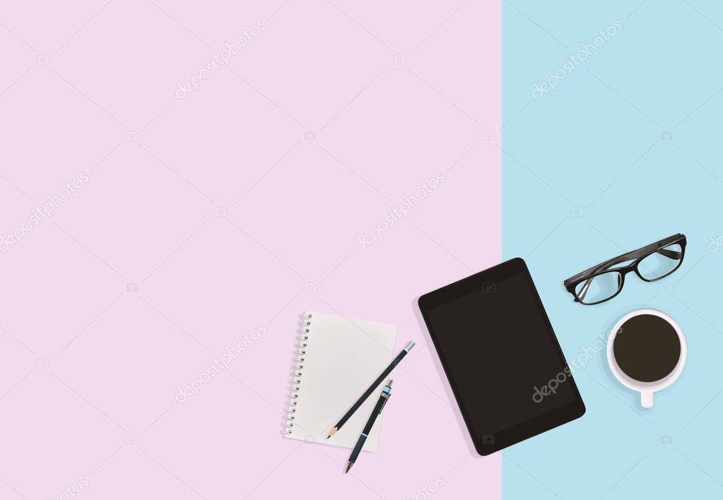 Modern office workplace pastel color desktop with tablet, eyeglasses, notebook, pen, pencils and a cup of black coffee with copy space. Business concept.