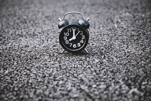 Black alarm clock with white number on the asphalt texture background texture with copy space.