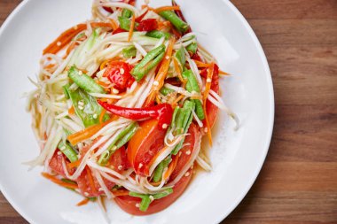 Thai food papaya salad or Somtam mixed with traditional ingredient herb sauce and red chili, tomato, long bean. Close-up. clipart