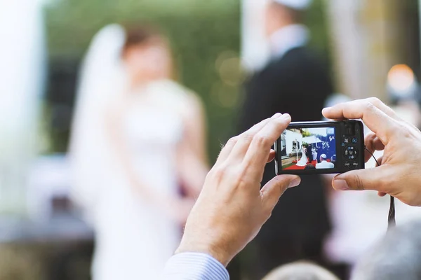 Bir kamera ile ortalama el alın gelin ve damat fotoğrafını düğün töreni sırasında