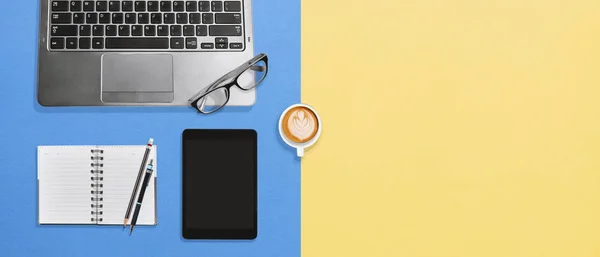 Escritorio de oficina con vista superior con computadora portátil, tableta, cuaderno en blanco y café sobre fondo colorido — Foto de Stock