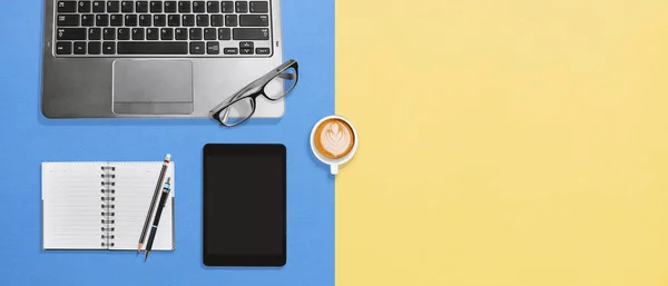 Bovenaanzicht Bureau met laptop, tablet, lege laptop en koffie op de kleurrijke achtergrond — Stockfoto