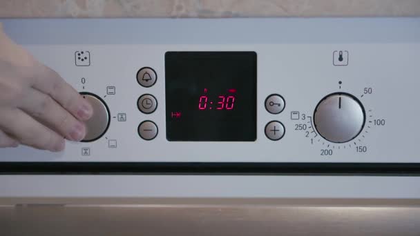 Female hand includes Metallic Toggle Switch of the Cooker Oven. Close-up View. Digital Clock of oven. Front panel of modern metalic oven, red indicators, new shiny buttons. Modern design in details. — Stock Video