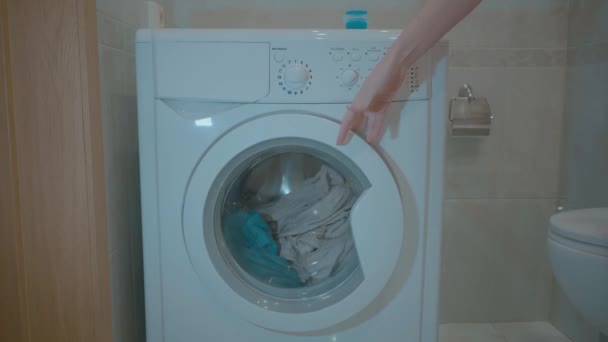 Womam está poniendo suavemente ropa colorida en la lavadora. Una joven cierra la puerta del pie de la lavadora. Vídeo 4k . — Vídeo de stock