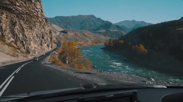 View from front window in the car, car is driving on empty mountain road, slow motion. Road trip at summer in Russia. View from the car on the mountains, river, road and trees. Slow motion. — Stock Video