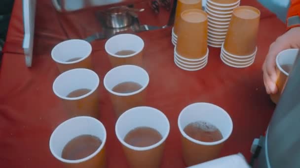 Female hand pours tea from a thermos. A plastic cup of tea is raised by a mans hand. Tea is poured on the street. Slow motion. — Stock Video
