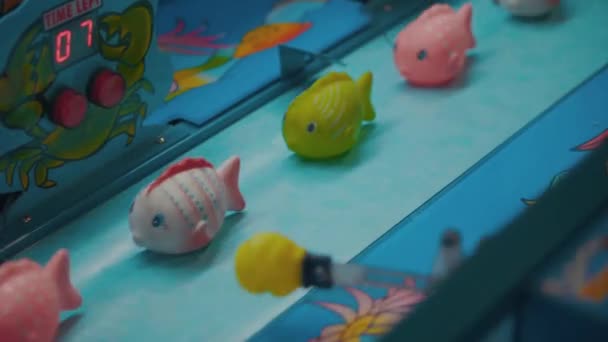 Máquina de juego para niños con peces de goma. El puño golpea un juguete en el parque de diversiones. Área de juego en video 4k. Pesca de peces de goma de captura . — Vídeo de stock