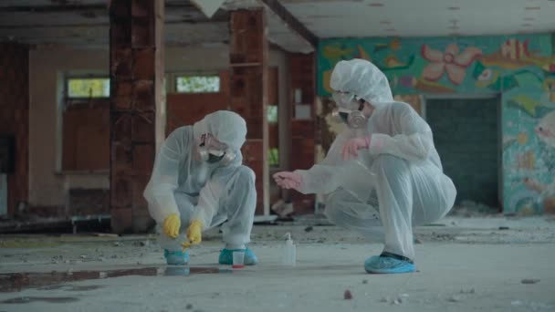 Duas pessoas a trabalhar numa área abandonada. Recolha provas em Chernobyl, Pripyat. As mulheres de fato de protecção branco verificam a ecologia. Espaço interior radioativo. 4k vídeo . — Vídeo de Stock