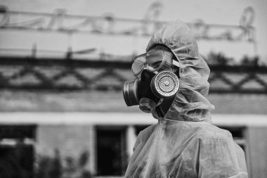 Bilim adamı radyasyona karşı bir solunum cihazı ve beyaz koruyucu elbise giydi. Ekolojiyi önemseyen bir kızın yakın plan profili. Coronavirus salgınında, COVID-19.