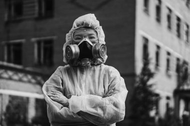 Asyalı görünümlü beyaz koruyucu kıyafetli bir bilim adamı ekolojiyle ilgilenir. Terk edilmiş bir bölgedeki bir kızın solunum cihazı. Coronavirus salgınında, COVID-19.