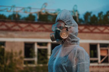 Bilim adamı radyasyona karşı bir solunum cihazı ve beyaz koruyucu elbise giydi. Ekolojiyi önemseyen bir kızın yakın plan profili. Coronavirus salgınında, COVID-19.