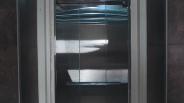 Asansör kapıları açılıyor. Kapıyı açmak bir asansördür. Metal kapılar sorunsuz bir şekilde açılıp kapanır. 4k video gümüş ve bej yeni asansör.