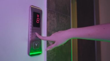 Genç Kadın Yukarı çıkmak için Asansör Düğmesine BasAr. Metal asansör. Parmak, ok işaretli olarak düğmeye basar. Yeşil ve pembe aydınlatma lambaları. 8, 7, 6, 5, 4 ve 3 kat.