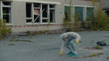 Terk edilmiş bir bölgedeki bir bilim adamı kanıt toplar. Coronavirus salgını, COVID-19. Radyasyon ve zararlı kirliliklere karşı koruyucu giysi. Solunum cihazındaki kız ekolojiyle ilgileniyor..