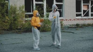 Bilim adamları solunum cihazını takıp rap klibi için dans ediyorlar. Coronavirus salgını, COVID-19. Radyasyon yüzünden koruyucu giysili kızlar müziğe yöneldi. Çevresel tema. Novosibirsk 'te terk edilmiş korkunç bir bölge..