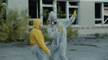 Bilim adamları solunum cihazını takıp rap klibi için dans ediyorlar. Coronavirus salgını, COVID-19. Radyasyon yüzünden koruyucu giysili kızlar müziğe yöneldi. Çevresel tema. Novosibirsk 'te terk edilmiş korkunç bir bölge..
