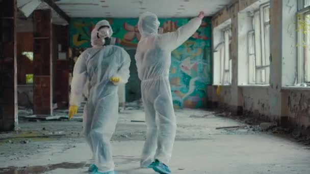 科学者たちはラップクリップのためにマスクとダンスをしました 放射線から音楽に移動する保護服の女の子 環境をテーマに ノヴォシビルスクのひどい放棄された領土 パンデミックにおけるコロナウイルス Covid — ストック動画