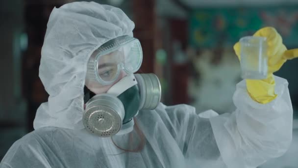 Un científico en una zona abandonada recoge pruebas. Coronavirus en pandemia, COVID-19. Cara protectora contra la radiación y las impurezas dañinas. Niñas en el cuidado respiratorio de la ecología. — Vídeo de stock