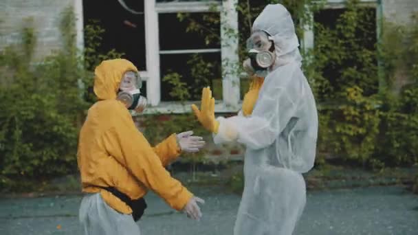 科学家们戴上呼吸器,为一个说唱片断跳舞.大流行病中的头孢病毒，COVID-19 。穿着防护服的女孩从辐射走向音乐。环境主题。Novosibirsk被遗弃的可怕领土. — 图库视频影像