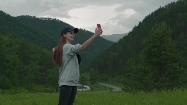 年轻的女孩在灰色毛衣对话视频聊天手机朋友连接山 互联网无处不在 山区交通良好 — 图库视频影像