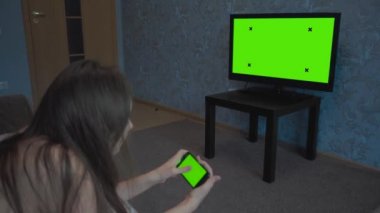 Kız yeşil bir ekran ile telefonda site üzerinden yapraklama olduğunu. Bir Tv krom anahtar odaya dahildir ve