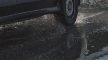 Yolda büyük bir çukur, su birikintisi ile dolu. Bir arabanın tekerleği toprakla dolu bir deliğe düşer. Rusya'da kötü yol. İlkbaharda yağmur ve kar dan sonra tozlu toprak yol.